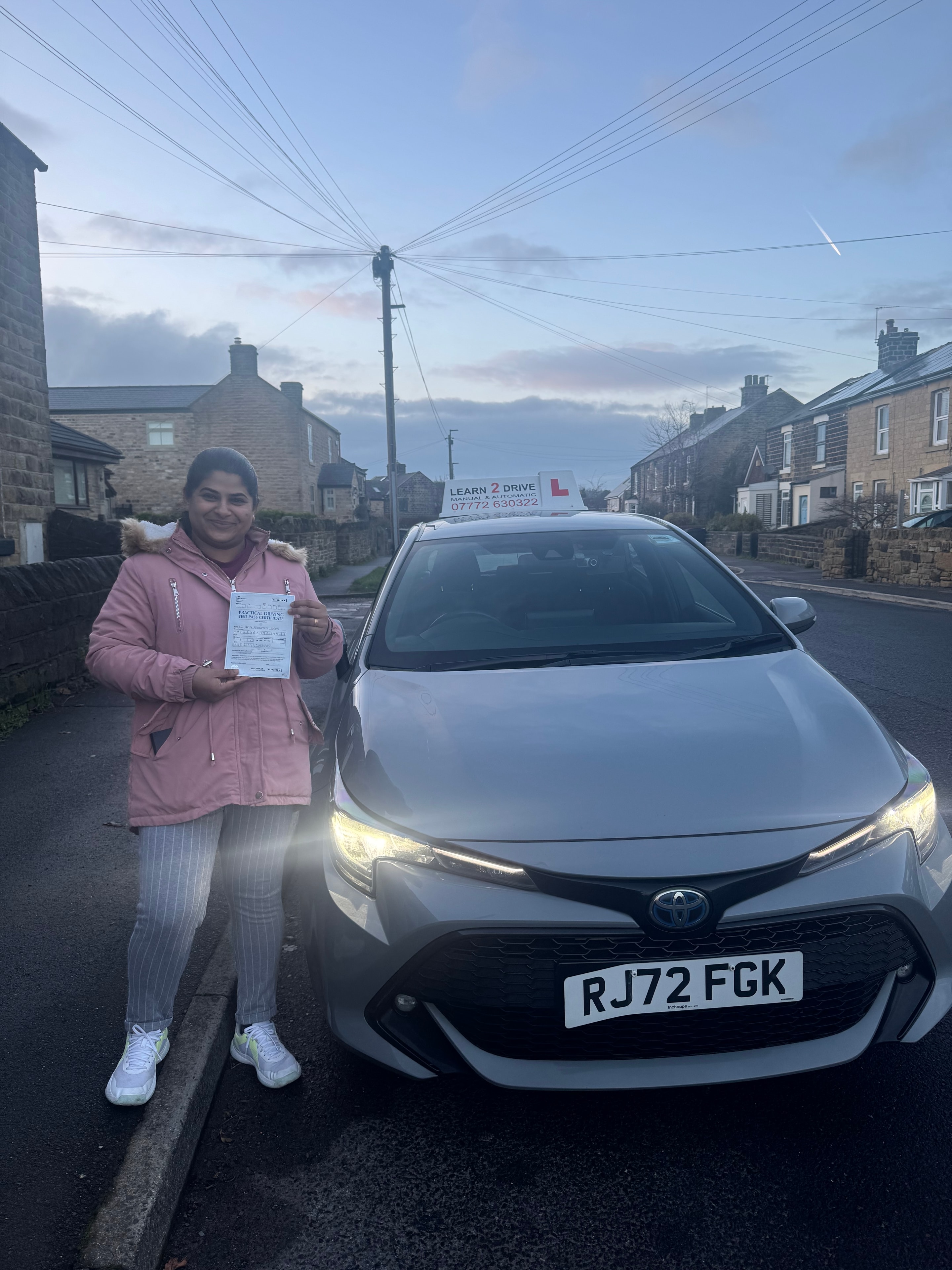 Student holding pass certificate next to Learn 2 Drive car