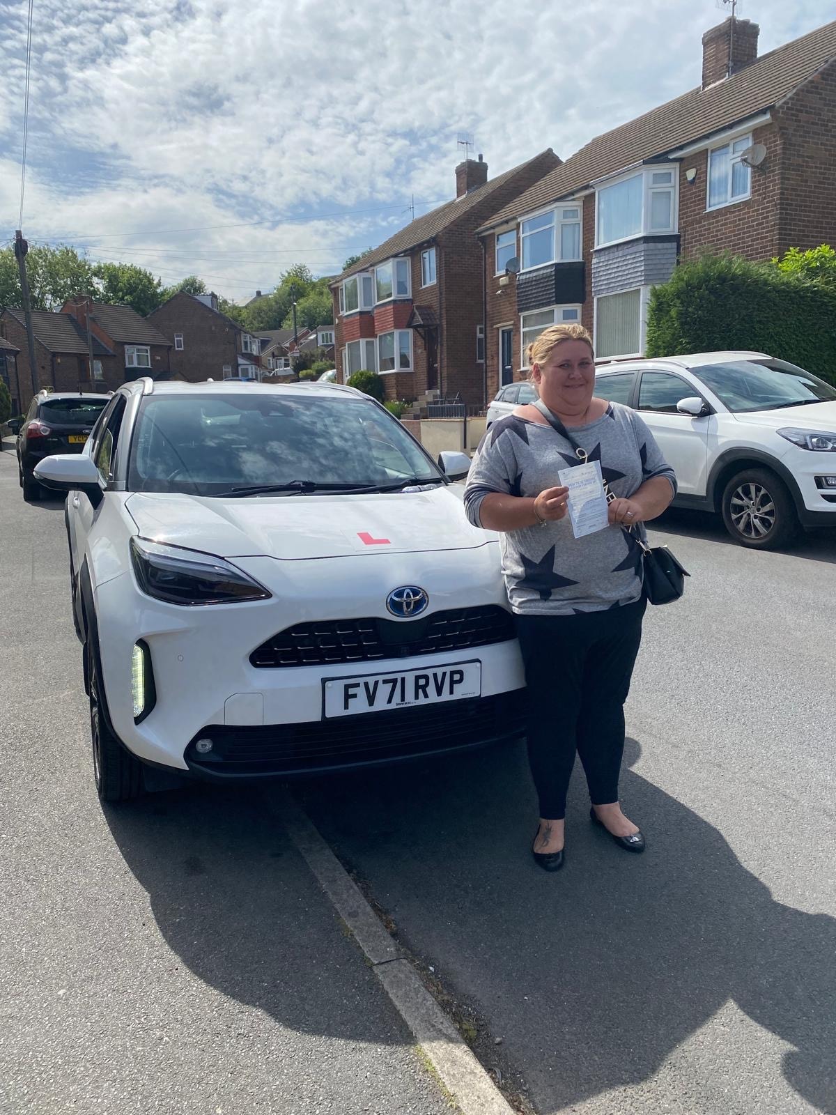 Student celebrating passing their driving test next to a Learn 2 Drive car