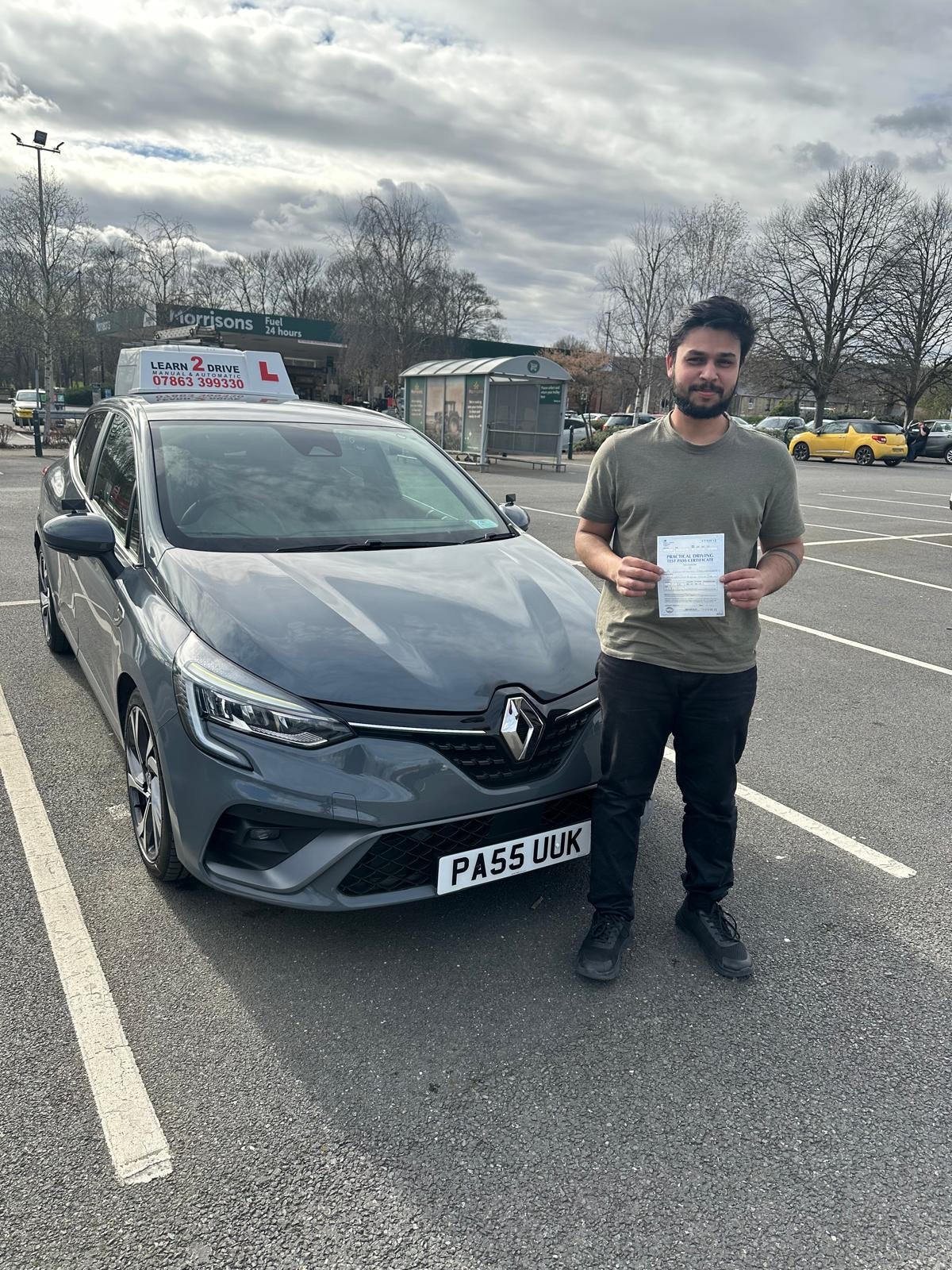 Student holding pass certificate next to a Learn 2 Drive car