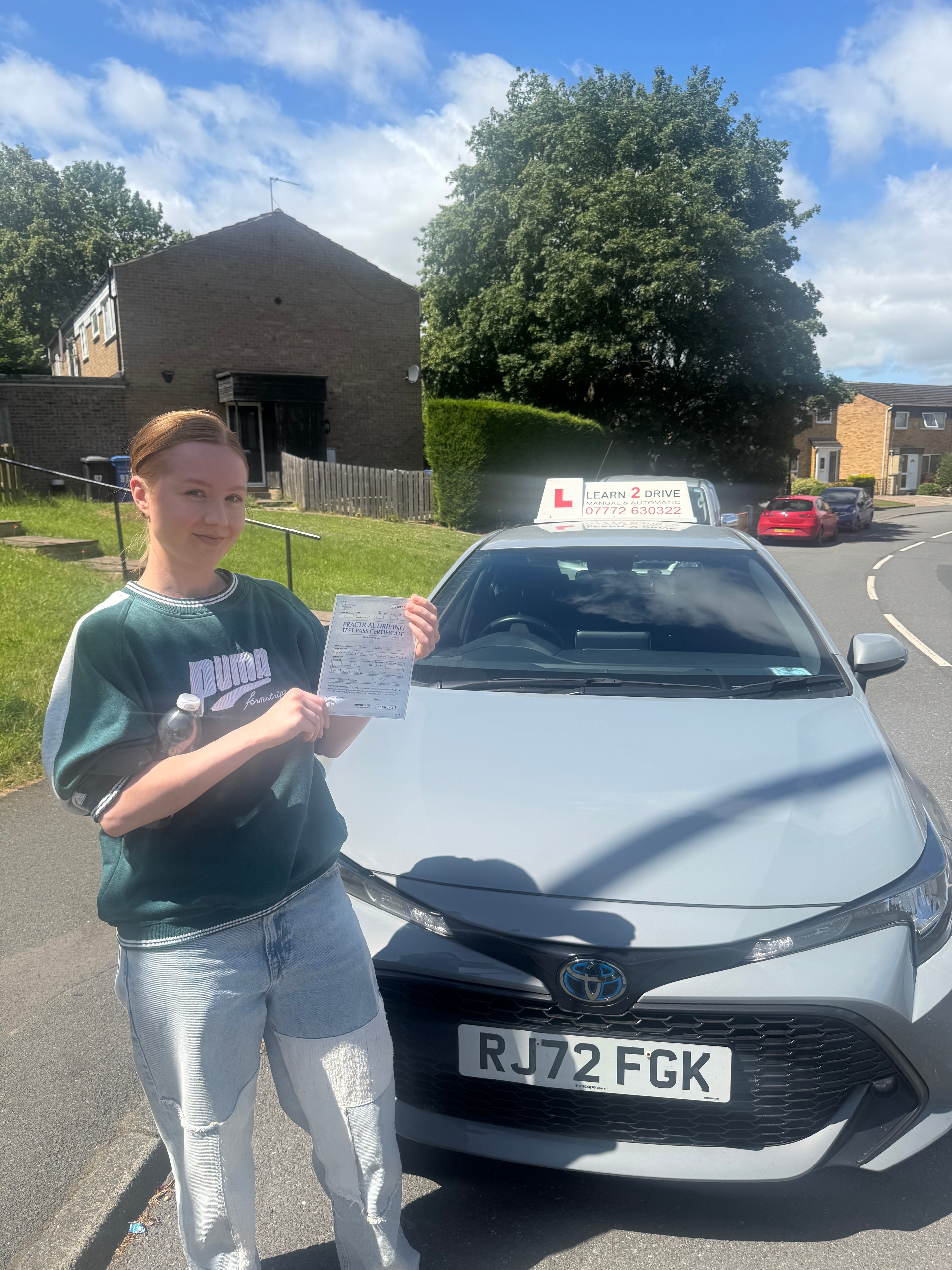 Student holding pass certificate next to Learn 2 Drive car