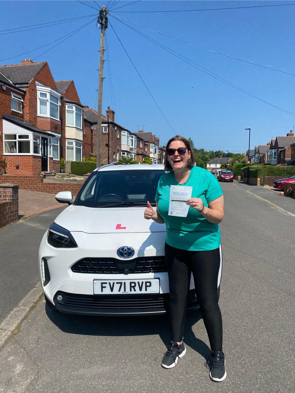 Student celebrating passing their driving test next to a Learn 2 Drive car